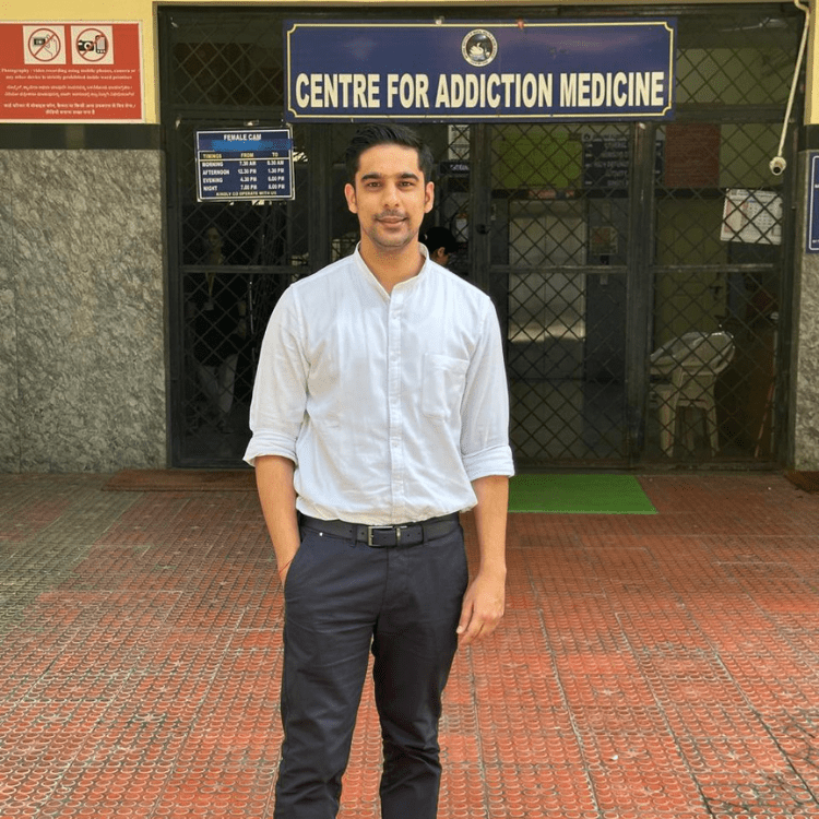 Dr Raghav Oza standing in front of the Centre for Addiction Medicine department entrance