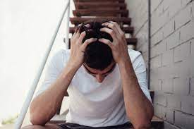 A person sitting on stairs with their hands on their head, symbolizing intense stress or mental turmoil.